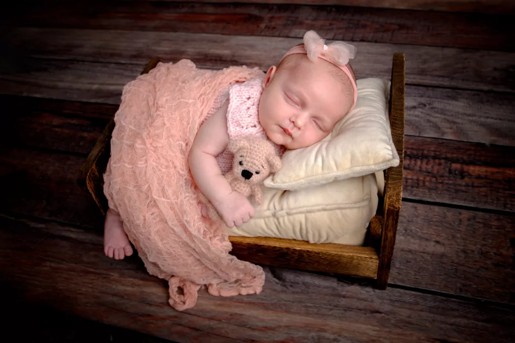 bébé fille endormie dans un petit lit en bois