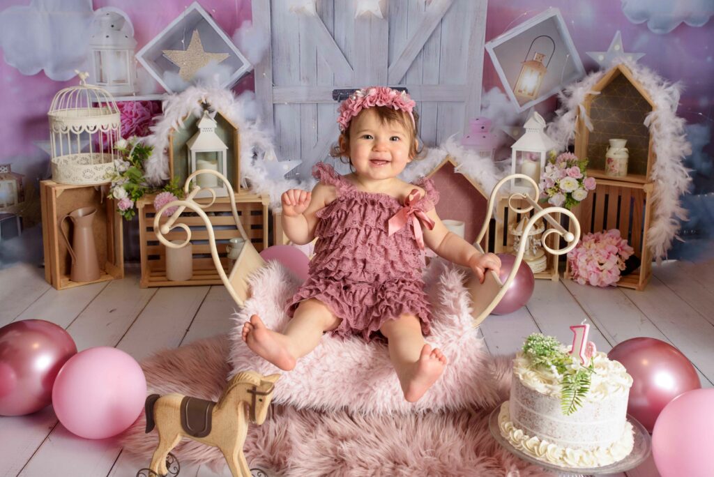 Bébé fille fêtent son anniversaire au studio dans un décors rose avec des ballons.