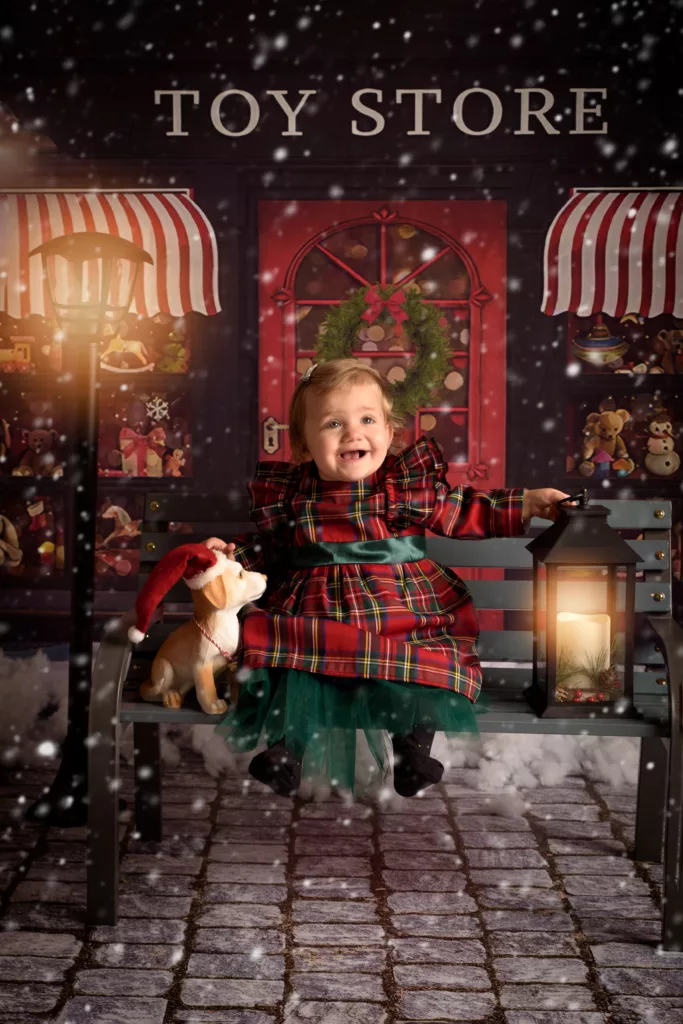 petite fille sur un banc devant une boutique de Noel