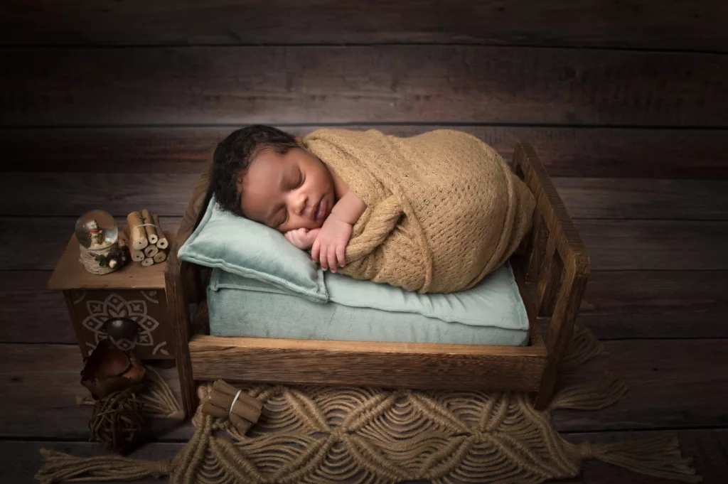 Bébé photographié endormi dans un petit lit en bois