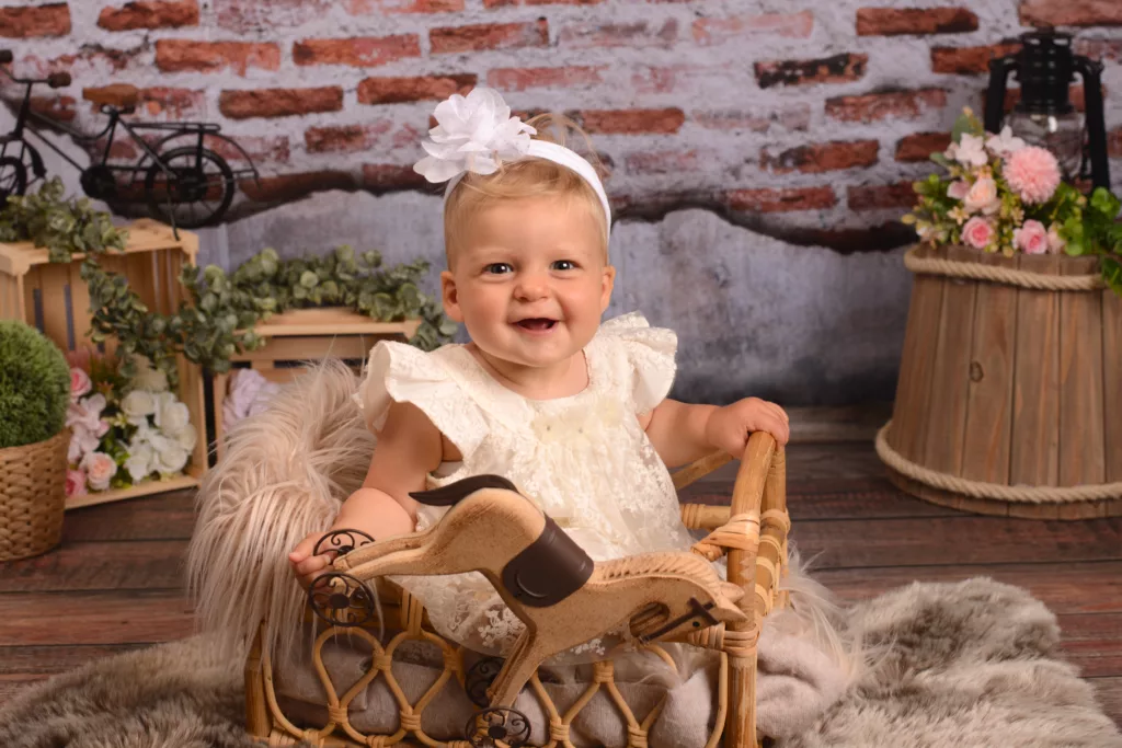 Bébé de 8 mois dans un petit panier avec un cheval de bois en jouet. Photo réalisée lors de sa séance photo chez studio tendresse photographie proche de thionville