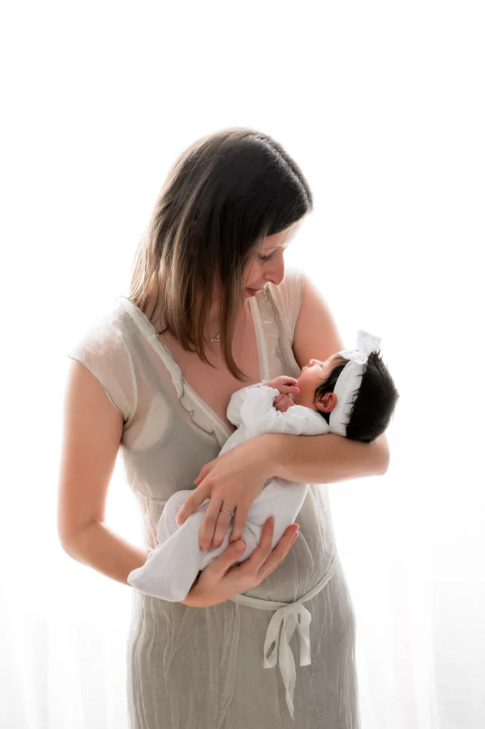 Maman tenant dans ses bras son bébé de 1 mois lors de séance photo