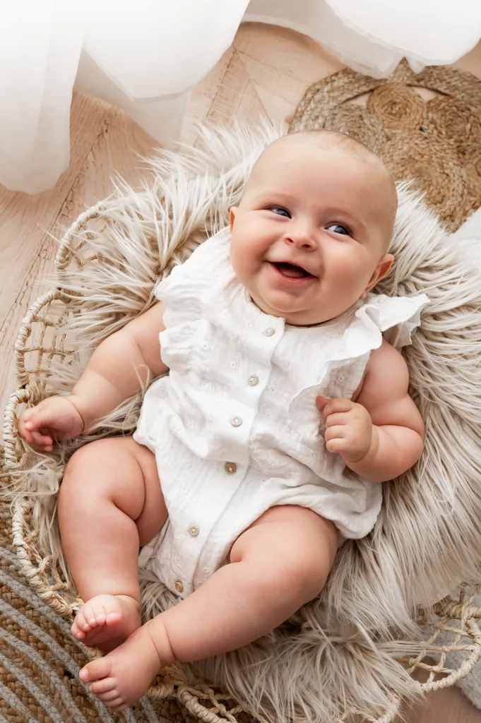 bébé souriant dans une tenue blanche